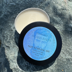 Mountain Escape Beard Balm open tin sitting on a rock