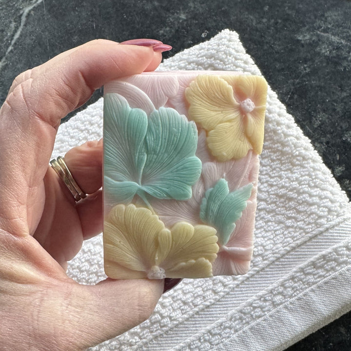 Hand holding Pink Plumeria Soap, showcasing top pattern.