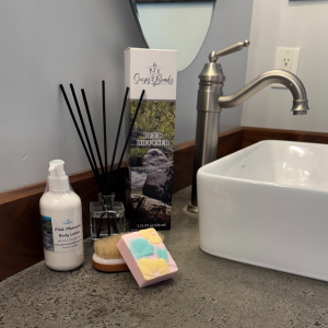 Pink Plumeria Collection in a rustic bathroom including soap, body lotion and reed diffuser