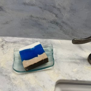 Beach scented soap resting on a soap dish on a marble counter