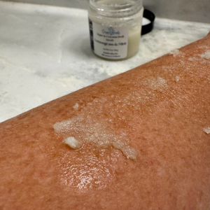 Forearm with sugar scrub on it and jar in background