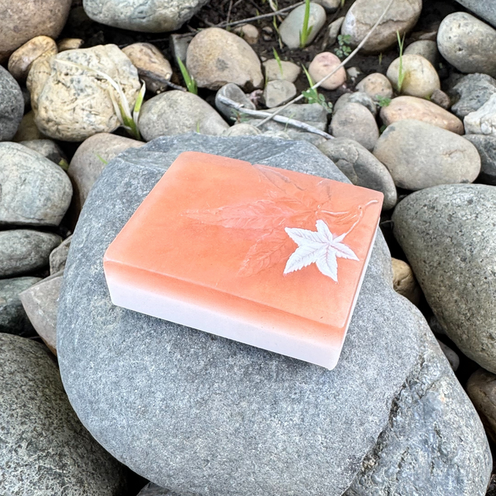 Soft Orangish Rust colored bar ar of soap with a  leaf design on a rock