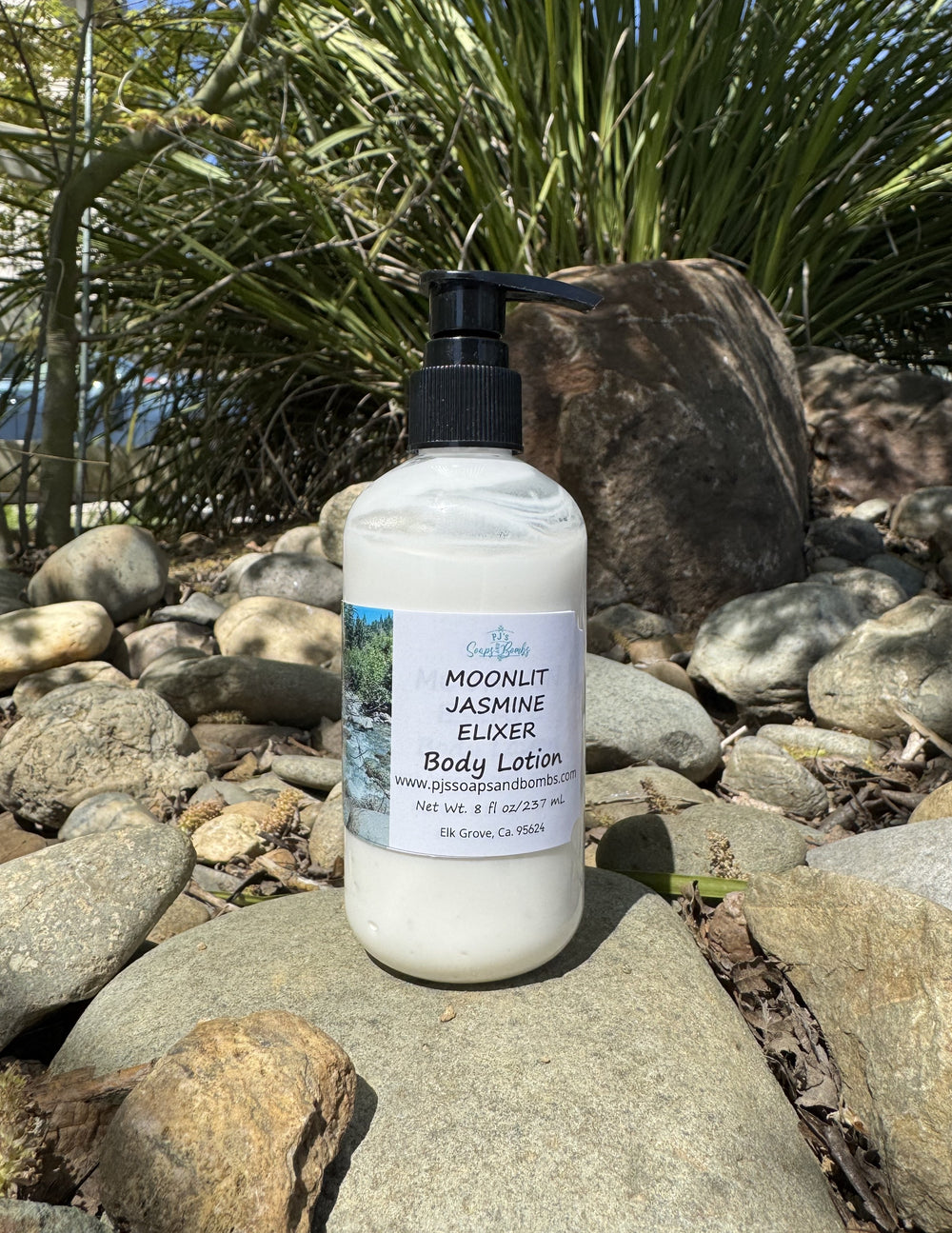 Moonlit Jasmine Elixer Body Lotion in natural setting sitting on a rock