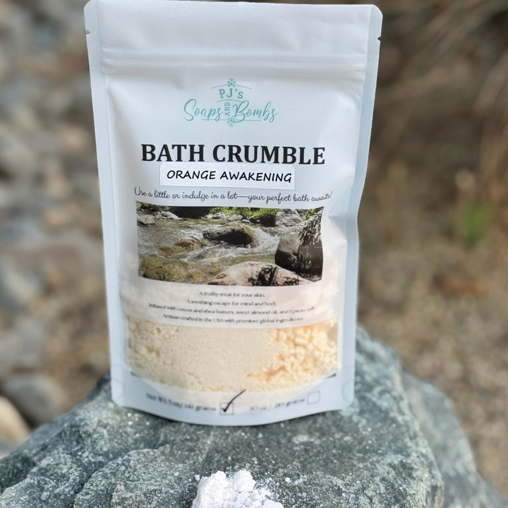 Bath crumble package labeled 'Orange Awakening' on a rock with a natural background