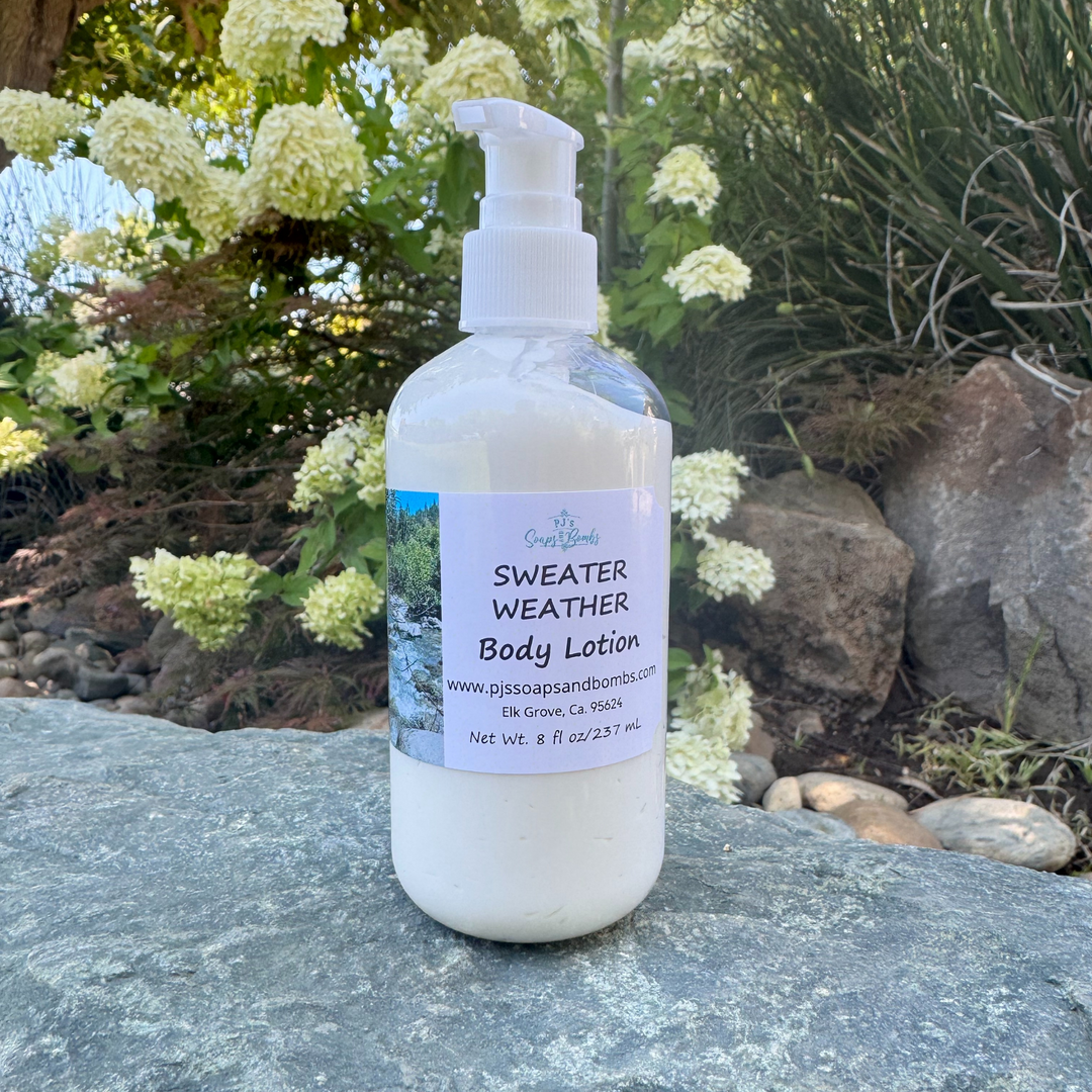 Body lotion bottle labeled 'Sweater Weather' on a rock with greenery in the background
