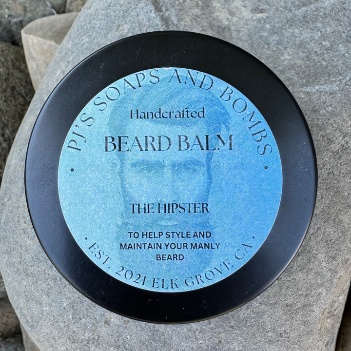 The Hipster Beard Balm Tin sitting on a rock 