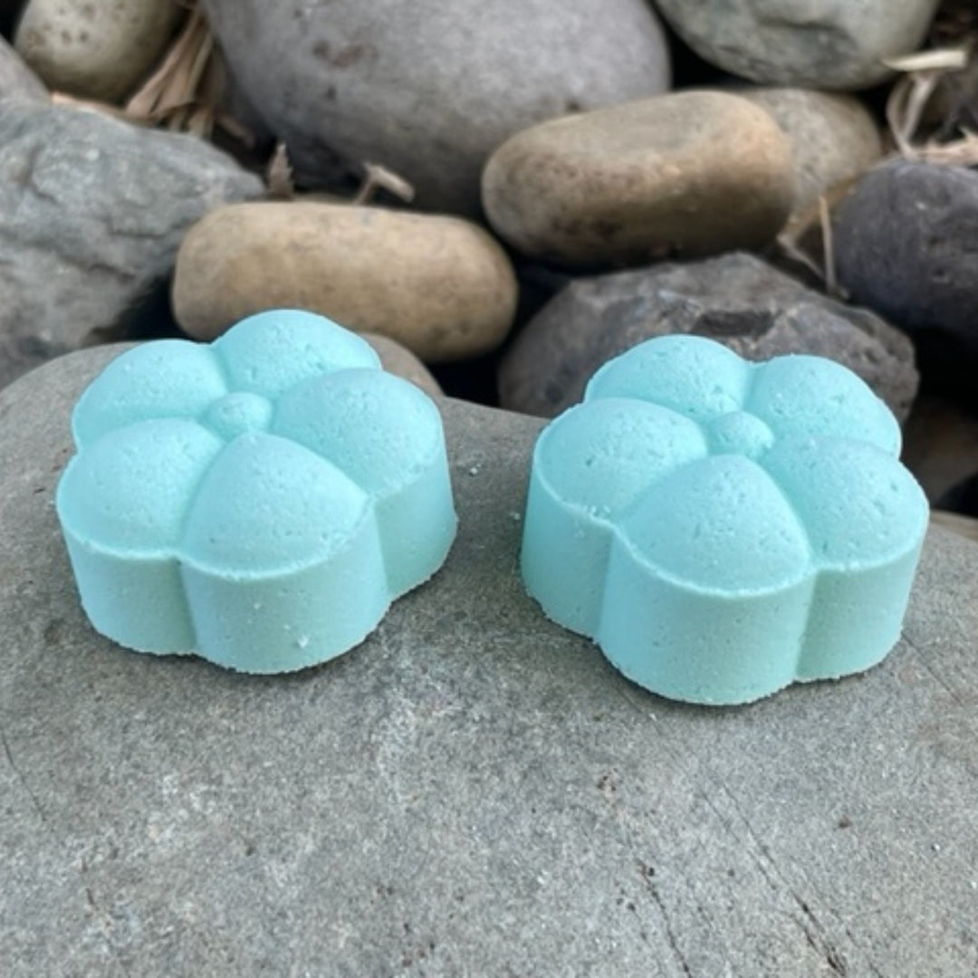 Two Tranquil Beach shower steamers sitting on a rock