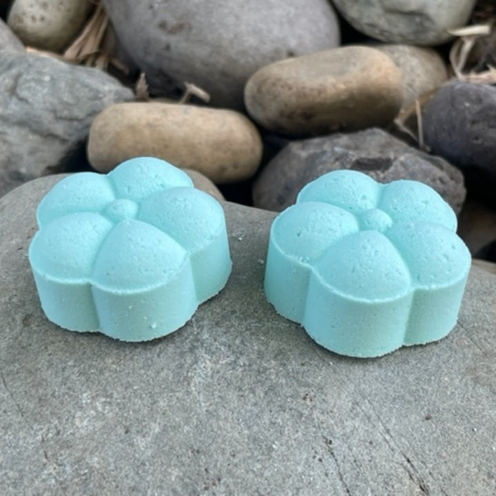 Two Tranquil Beach shower steamers sitting on a rock