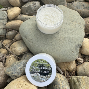 Tranquil Beach Sugar Scrub in an open jar sitting on a rock in a natural enviornment