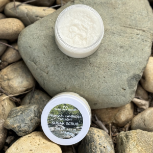 Tranquil Lavender Twilight Sugar Scrub open jar sitting on a rock in a natural environment