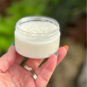Open Jar of Sugar Scrub being held by fingertips