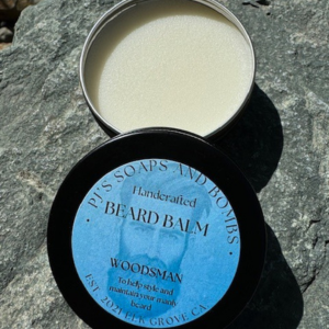Woodsman Beard Balm open tin with label on lid showing sitting on a rock